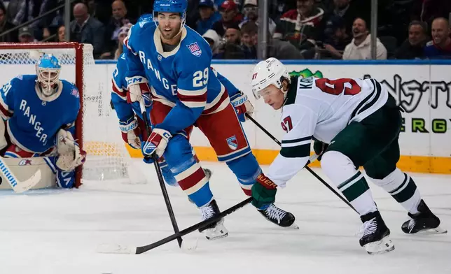 Minnesota Wild's Kirill Kaprizov (97) fights for control of the puck with New York Rangers' Matthew Robertson (29) during the second period of an NHL hockey game Monday, Oct. 20, 2025, at Madison Square Garden in New York. (AP Photo/Frank Franklin II)