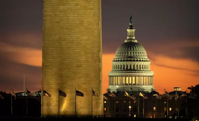 The base of the Washington Monument and the dome of the U.S. Capitol are seen at dawn on Wednesday, Oct. 1, 2025, in Washington. (AP Photo/Mark Schiefelbein)