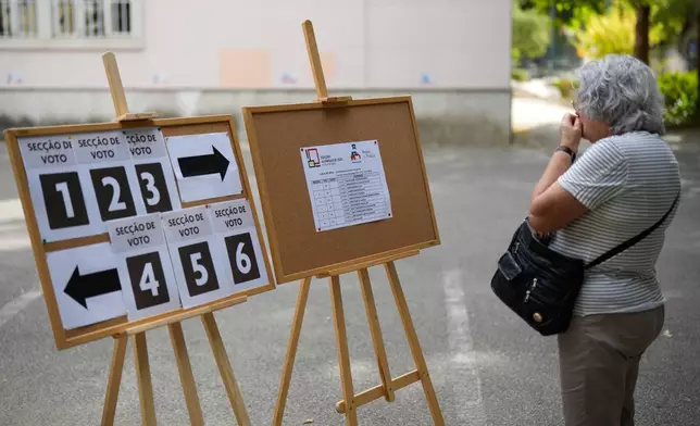 A woman checks where to vote at a polling station for Portugal's municipal elections in Lisbon, Sunday, Oct. 12, 2025. (AP Photo/Armando Franca)
