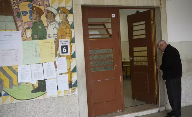 A man waits his turn to vote next to a mural from Portugal's fascist period at a polling station for Portugal's municipal elections in Lisbon, Sunday, Oct. 12, 2025. (AP Photo/Armando Franca)