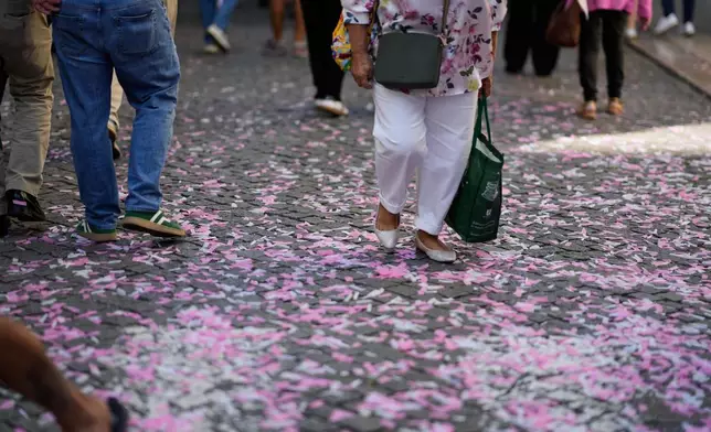 People walk on confetti left behind by supporters of the left-of-center coalition Viver Lisboa, (To Live Lisbon), campaigning in downtown Lisbon ahead of Sunday's municipal elections, Friday, Oct. 10, 2025. (AP Photo/Armando Franca)