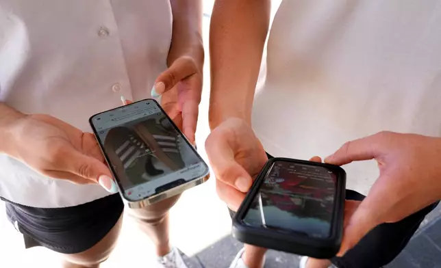 FILE - 14-year-old Henry, right, and Angel, 15, use their phones to view social media in Sydney, on Nov. 8, 2024. (AP Photo/Rick Rycroft, File)