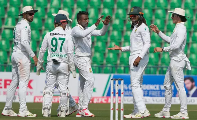 South Africa's Senuran Muthusamy, center, celebrates with teammates after taking the wicket of Pakistan's Abdullah Shafique during the third day of the first test cricket match between Pakistan and South Africa, in Lahore, Pakistan, Tuesday, Oct. 14, 2025. (AP Photo/K.M. Chaudary)
