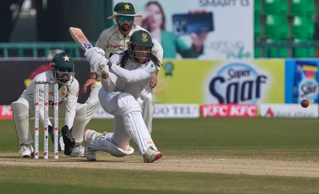 South Africa's Tony dy Zorzi, front, plays a shot, as Pakistan Mohammad Rizwan, left, and Salman Ali Agha watch during the third day of the first test cricket match between Pakistan and South Africa, in Lahore, Pakistan, Tuesday, Oct. 14, 2025. (AP Photo/K.M. Chaudary)