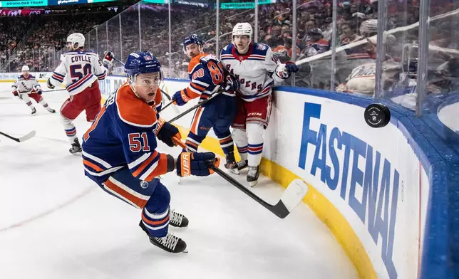 New York Rangers' Urho Vaakanainen (18) and Edmonton Oilers' Andrew Mangiapane (88) battle as Oilers' Troy Stecher (51) goes after the puck during third-period NHL hockey game action in Edmonton, Alberta, Thursday, Oct. 30, 2025. (Jason Franson/The Canadian Press via AP)