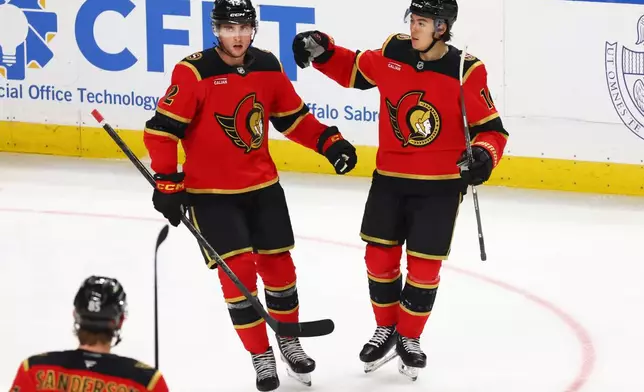 Ottawa Senators center Shane Pinto (12) celebrates his goal with defenseman Jordan Spence (10) during the third period of an NHL hockey game against the Buffalo Sabres Wednesday, Oct. 15, 2025, in Buffalo, N.Y. (AP Photo/Jeffrey T. Barnes)