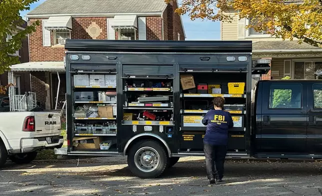 An FBI agent stands by an Evidence Response Team truck outside a home in a Dearborn, Mich., neighborhood on Friday, Oct. 31, 2025. (AP Photo/Mike Householder)