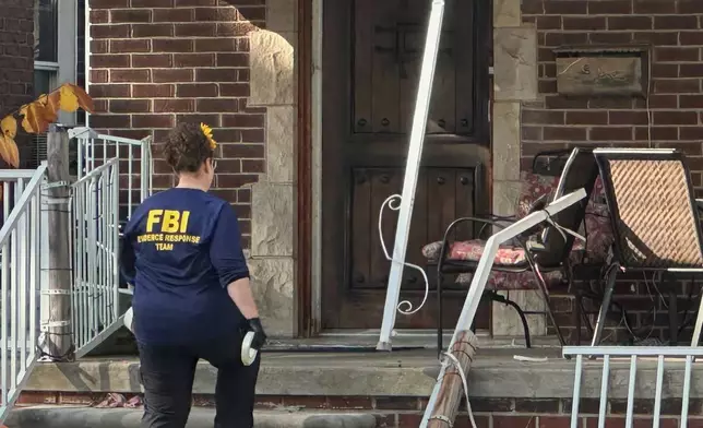 An FBI agent enters a home in a Dearborn, Mich., neighborhood on Friday, Oct. 31, 2025. (AP Photo/Mike Householder)