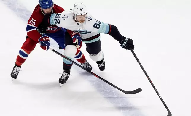Montreal Canadiens' Alex Newhook (15) and Seattle Kraken's Brandon Montour (62) battle for the puck during second period NHL hockey action in Montreal on Tuesday, Oct. 14, 2025. (Christinne Muschi/The Canadian Press via AP)