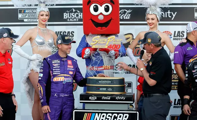 Ryan Growney, center right, general manager of the South Point Hotel and Casino, presents the trophy to Denny Hamlin, center left, in Victory Lane after Hamlin won a NASCAR Cup Series auto race Sunday, Oct. 12, 2025, in Las Vegas. (AP Photo/Steve Marcus)