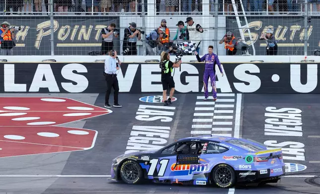Denny Hamlin picks up the checkered flag after winning a NASCAR Cup Series auto race Sunday, Oct. 12, 2025, in Las Vegas. (AP Photo/Steve Marcus)