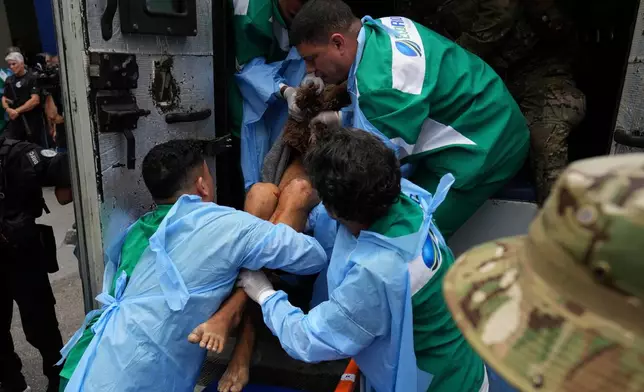 Getulio Vargas Hospital workers remove an injured person from a police truck after he was injured in a police operation against alleged drug traffickers in the Complexo do Alemao favela where the criminal organization "Comando Vermelho" operates in Rio de Janeiro, Tuesday, Oct. 28, 2025. (AP Photo/Silvia Izquierdo)
