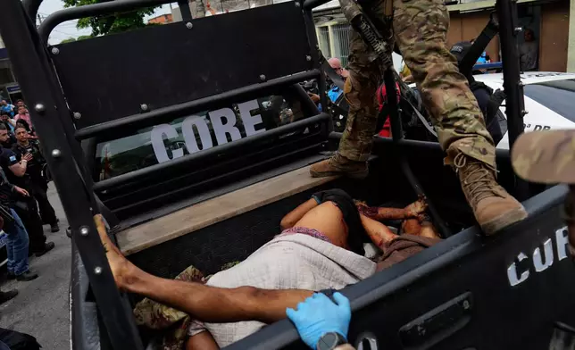 EDS NOTE: GRAPHIC CONTENT - A police officer stands over bloodied people lying in the back of a police truck brought to the Getulio Vargas Hospital during a police operation against alleged drug traffickers in the Complexo do Alemao favela where the criminal organization "Comando Vermelho" operates in Rio de Janeiro, Tuesday, Oct. 28, 2025. (AP Photo/Silvia Izquierdo)