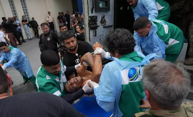 EDS NOTE: GRAPHIC CONTENT - Getulio Vargas Hospital workers remove an injured person from a police truck after he was injured during a police operation against alleged drug traffickers in the Complexo do Alemao favela where the criminal organization "Comando Vermelho" operates in Rio de Janeiro, Tuesday, Oct. 28, 2025. (AP Photo/Silvia Izquierdo)