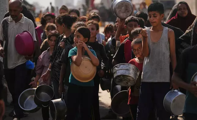 Palestinians wait to receive donated food at a community kitchen in Gaza City, Thursday, Oct. 23, 2025. (AP Photo/Abdel Kareem Hana)
