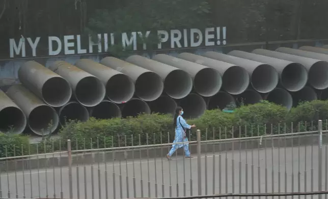 A woman wears a face mask as she walks amidst morning smog a day after Diwali festival in New Delhi, India, Tuesday, Oct. 21, 2025. (AP Photo/Manish Swarup)