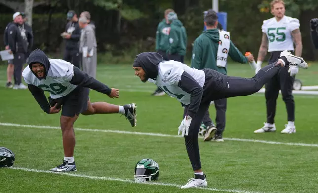 New York Jets linebacker Jermaine Johnson II (11), right, stretches during NFL football practice at The Grove in Watford, England, Friday, Oct. 10, 2025. (AP Photo/Kin Cheung)