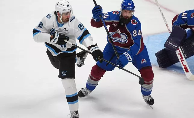 Utah Mammoth center Jack McBain, left, shoots the puck past Colorado Avalanche defenseman Brent Burns in the third period of an NHL hockey game Thursday, Oct. 9, 2025, in Denver. (AP Photo/David Zalubowski)
