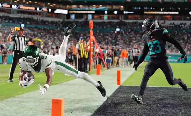 New York Jets wide receiver Garrett Wilson (5) lands out of bounds after catching a pass in front of Miami Dolphins cornerback Jack Jones (23) that was ruled no catch due to pass interference in the second half of an NFL football game, Monday, Sept. 29, 2025, in Miami Gardens, Fla. (AP Photo/Rebecca Blackwell)