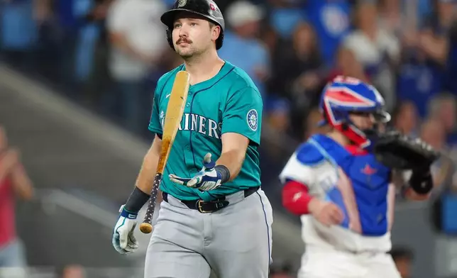 Seattle Mariners' Cal Raleigh, left, reacts after striking out against the Toronto Blue Jays during the sixth inning in Game 6 of baseball's American League Championship Series in Toronto, Sunday, Oct. 19, 2025. (Frank Gunn/The Canadian Press via AP)