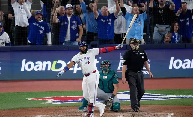 Toronto Blue Jays' Vladimir Guerrero Jr. watches his solo home run take flight against the Seattle Mariners during the fifth inning in Game 6 of baseball's American League Championship Series, Sunday, Oct. 19, 2025, in Toronto. (AP Photo/David J. Phillip)