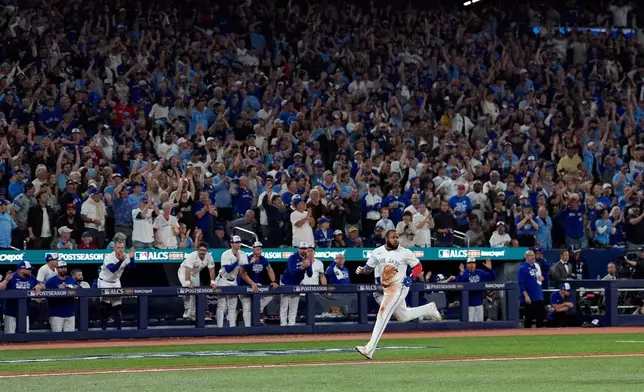 Toronto Blue Jays' Vladimir Guerrero Jr. scores on after throwing error during the seventh inning in Game 6 of baseball's American League Championship Series against the Seattle Mariners, Sunday, Oct. 19, 2025, in Toronto. (AP Photo/David J. Phillip)