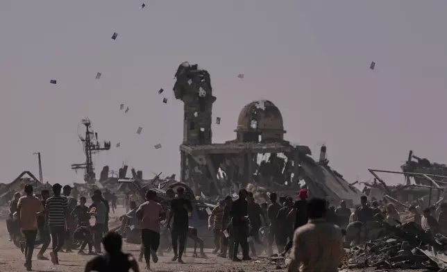 Palestinians collect leaflets dropped by an Israeli drone warning people to stay away from the so-called yellow line in Khan Younis, in the southern Gaza Strip, Monday, Oct. 20, 2025. (AP Photo/Jehad Alshrafi)