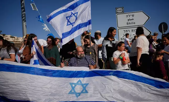 People gather to welcome freed Israeli hostage, Avinatan Or, who was recently released from Hamas captivity in Gaza, as he return from the hospital to his home at the West Bank settlement of Shilo, Tuesday, Oct. 21, 2025. (AP Photo/Ohad Zwigenberg)