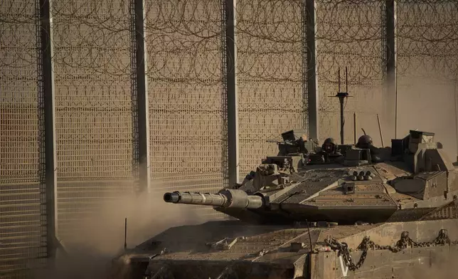 Israeli soldiers move on top of a tank along the Israeli-Gaza border as seen from southern Israel, Tuesday, Oct. 21, 2025. (AP Photo/Leo Correa)