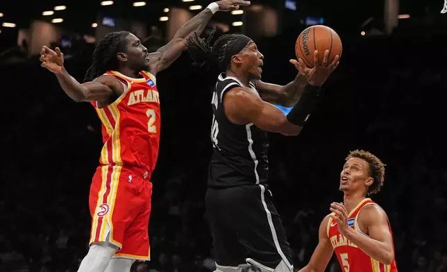 Brooklyn Nets' Terance Mann (14) drives past Atlanta Hawks' Keaton Wallace (2) and Dyson Daniels (5) during the second half of an NBA basketball game Wednesday, Oct. 29, 2025, at Barclays Center in New York. (AP Photo/Frank Franklin II)