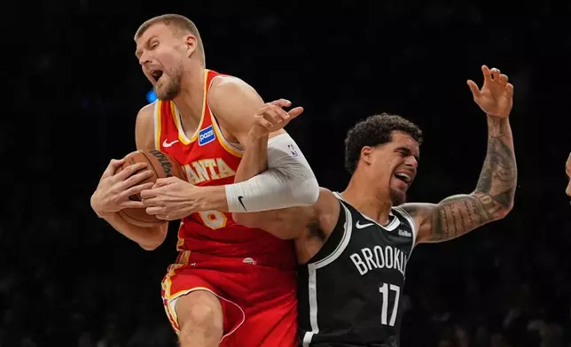Atlanta Hawks' Kristaps Porziņģis (8) fights for control of the ball with Brooklyn Nets' Michael Porter Jr. (17) during the second half of an NBA basketball game Wednesday, Oct. 29, 2025, at Barclays Center in New York. (AP Photo/Frank Franklin II)