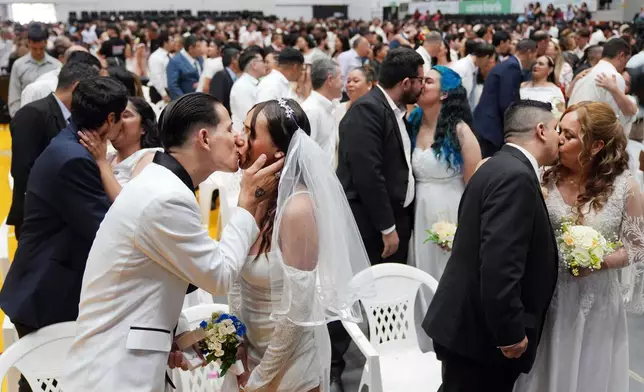 Jonathan Garay, left, kisses Fiorella Riveros during a group wedding ceremony organized by the Civil Registry to legally formalize their unions in in Asuncion, Paraguay, Saturday, Oct. 4, 2025. (AP Photo/Jorge Saenz)