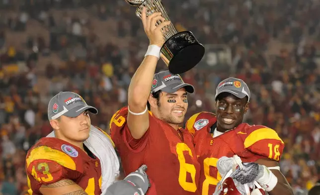 FILE - In this Jan. 1, 2009, file photo, Southern California quarterback Mark Sanchez (6) holds up the trophy as he celebrates with teammates Kaluka Maiava, left, and Damian Williams (18) after USC beat Penn State 38-24 in the Rose Bowl NCAA college football game, in Pasadena, Calif. (AP Photo/Mark J. Terrill, File)