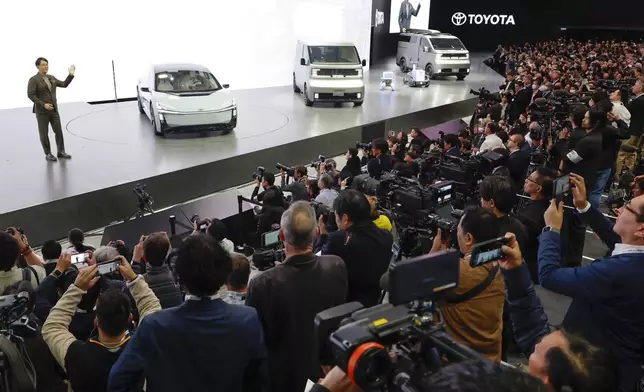 Toyota's President and CEO Koji Sato, left, speaks to the media beside Toyota vehicles on display at Tokyo Mobility Show during a press day at Tokyo Big Sight in Tokyo, on Wednesday, Oct. 29, 2025. (Daiki Katagiri/Kyodo News via AP)