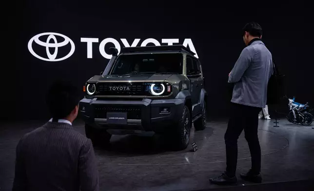 Members of the media and guests look at Toyota's Land Cruiser 'FJ' during the press day of the Japan Mobility Show, in Tokyo, Thursday, Oct. 30, 2025. (AP Photo/Louise Delmotte)