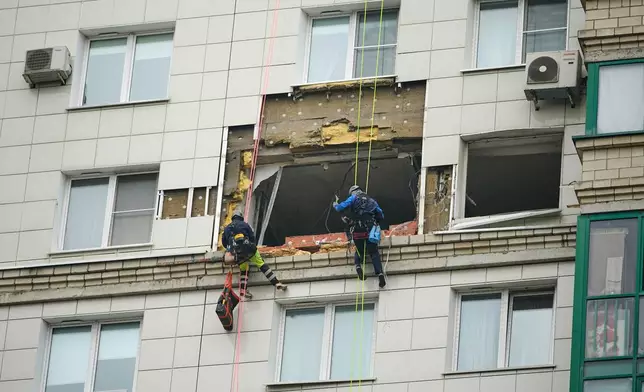 Municipal employees work at the side of a damaged multi-storey apartment building hit by a Ukrainian drone in Krasnogorsk, just outside Moscow, Russia, on Friday, Oct. 24, 2025. (AP Photo/Pavel Bednyakov)