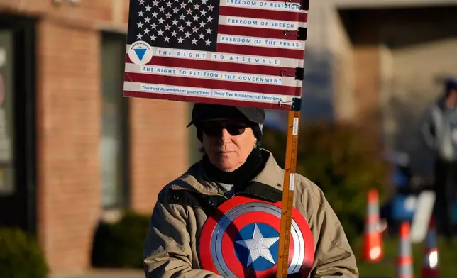 Jeanette Mancusi holds a flag as protesters gather outside an ICE processing facility in Broadview, Ill. a suburb of Chicago, Friday, Oct. 24, 2025. (AP Photo/Nam Y. Huh)