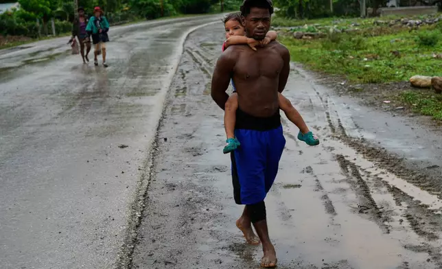 People evacuate before the the arrival of Hurricane Melissa in Canizo, a community in Santiago de Cuba, Tuesday, Oct. 28, 2025. (AP Photo/Ramón Espinosa)
