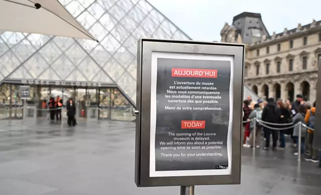 A board reads that the opening of the Louvre museum is delayed, but it remains closed for the day after Sunday's jewels robbery, Monday, Oct. 20, 2025 in Paris. (AP Photo/Emma Da Silva)