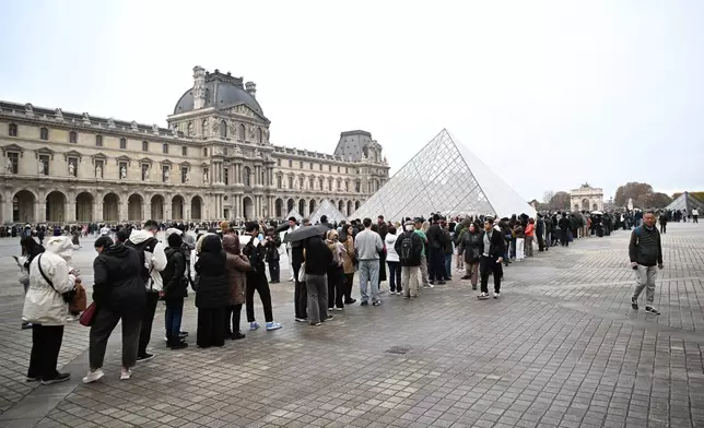 People queue outside the Louvre museum that remains closed for the day after Sunday's jewels robbery, Monday, Oct. 20, 2025 in Paris. (AP Photo/Emma Da Silva)