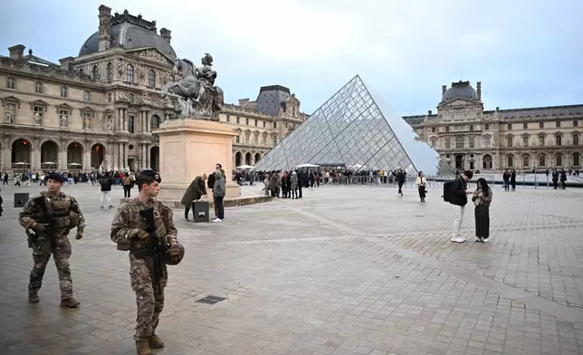 Soldiers patrol as people queue to enter the Louvre museum that remains closed for the day after Sunday's jewels robbery, Monday, Oct. 20, 2025 in Paris. (AP Photo/Emma Da Silva)