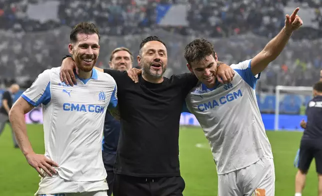 Marseille's head coach Roberto De Zerbi, centre, Marseille's Pierre-Emile Hojbjerg, left, Marseille's Matt O'Riley celebrate their victory after the French League One soccer match between Marseille and Paris Saint-Germain at Orange Velodrome in Marseille, France, Monday, Sept. 22, 2025. (AP Photo/Philippe Magoni)