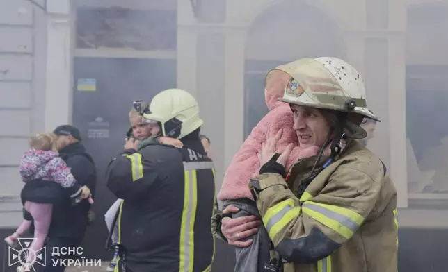 In this photo provided by the Ukrainian Emergency Service, rescuers evacuate children after Russian drones hit a city kindergarten during an attack in Kharkiv, Ukraine, Wednesday, Oct. 22, 2025. (Ukrainian Emergency Service via AP)