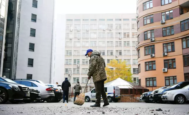 Bohdan Romaniv, 80, sweeps debris outside an apartment building that Russian attacks damaged, Wednesday, Oct. 22, 2025, in Kyiv, Ukraine. (AP Photo/Julia Demaree Nikhinson)