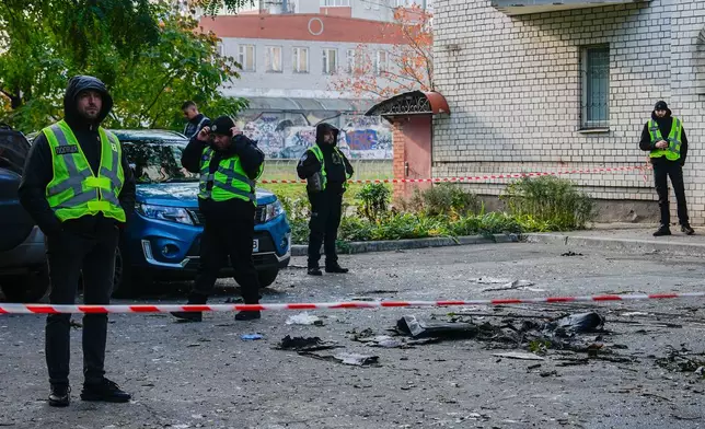 Police standby as debris lies on the ground outside an apartment building that Russian attacks damaged, Wednesday, Oct. 22, 2025, in Kyiv, Ukraine. (AP Photo/Julia Demaree Nikhinson)