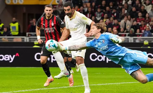 Pisa's goalkeeper Adrian Šemper, right, dives out to make a save as defender Raúl Albiol, center, backs up the play during the Serie A soccer match between AC Milan and Pisa in Milan, Italy, Friday, Oct. 24, 2025. (Fabio Ferrari /LaPresse via AP)