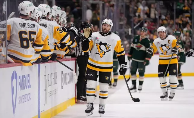 Pittsburgh Penguins right wing Bryan Rust (17) celebrates with teammates after scoring a goal during the third period of an NHL hockey game against the Minnesota Wild, Thursday, Oct. 30, 2025, in St. Paul, Minn. (AP Photo/Abbie Parr)