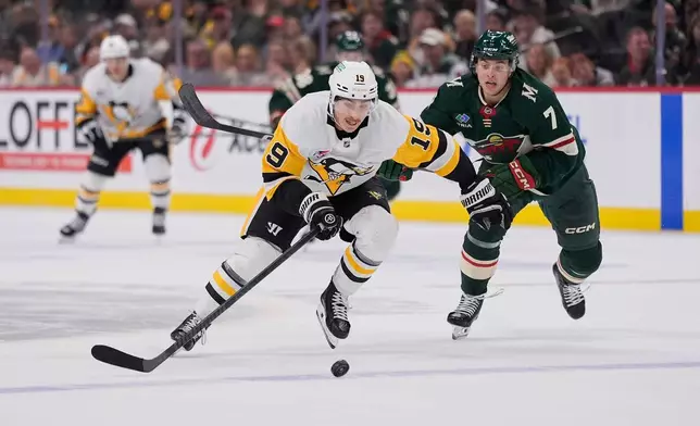 Pittsburgh Penguins center Connor Dewar (19) skates with the puck as Minnesota Wild defenseman Brock Faber (7) defends during the second period of an NHL hockey game, Thursday, Oct. 30, 2025, in St. Paul, Minn. (AP Photo/Abbie Parr)