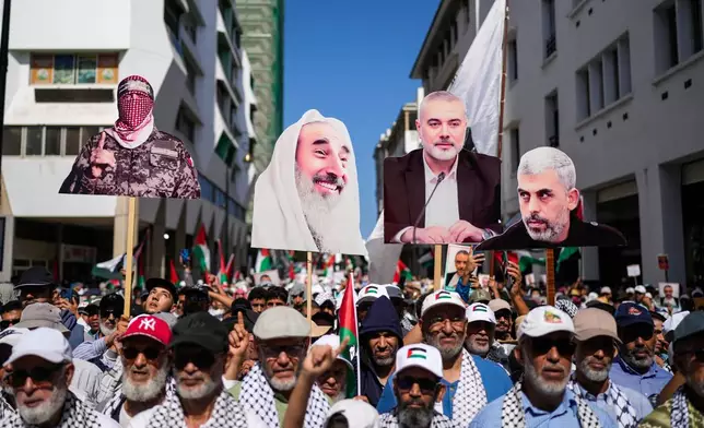 People carry photos of Hamas leaders as tens of thousands take part in a march in support of Palestinians in Gaza and against normalization with Israel, in Rabat, Morocco, Sunday, Oct. 5, 2025. (AP Photo/Mosa'ab Elshamy)