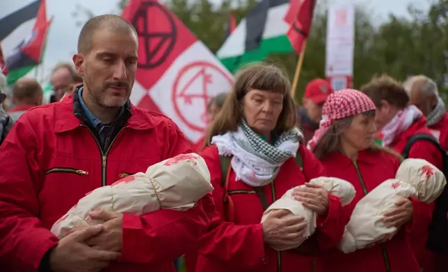 Protesters mimick holding the bodies of children demanding their government do more to halt Israel's campaign in Gaza, during a demonstration in Amsterdam, Netherlands, Sunday, Oct. 5, 2025. (AP Photo/Peter Dejong)